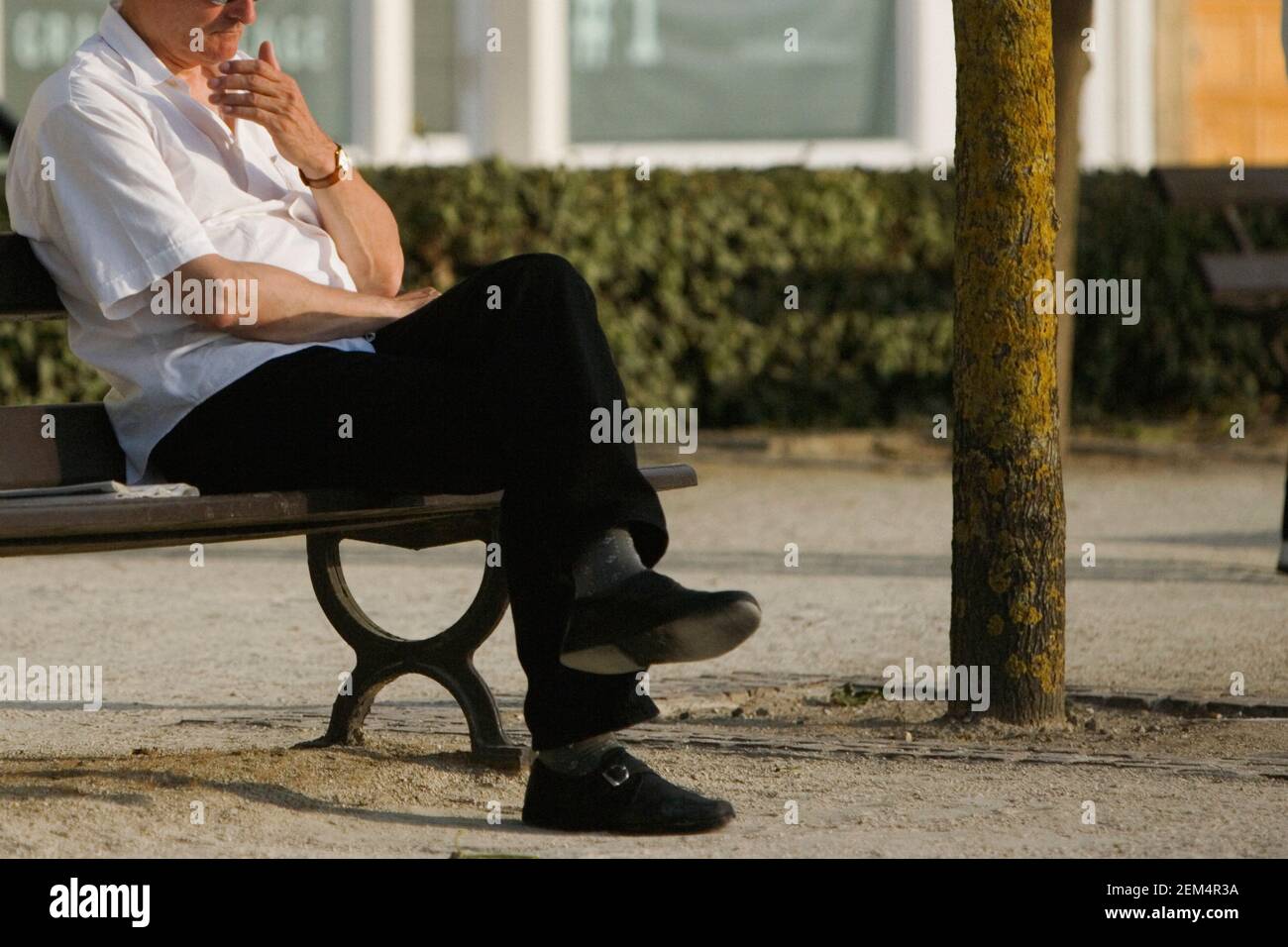 Uomo maturo seduto con le gambe incrociate e pensando Foto Stock
