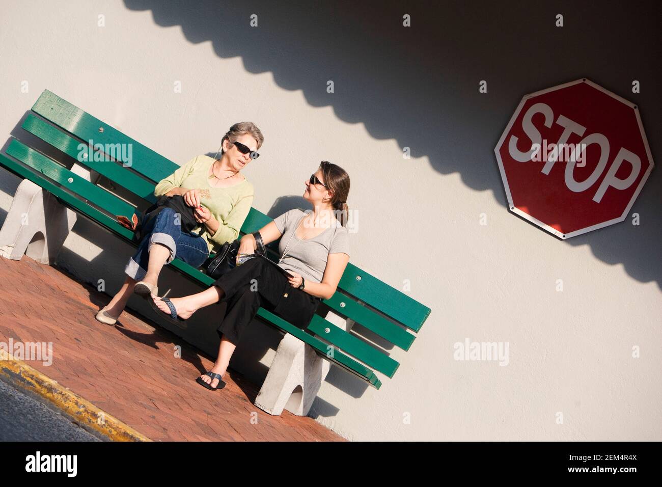Giovane donna e madre seduta su una panchina Foto Stock