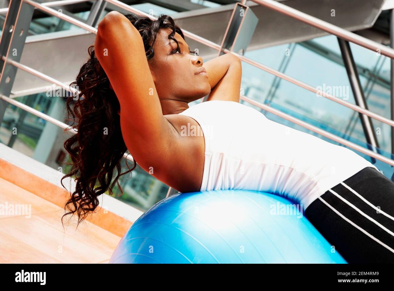 Profilo laterale di una giovane donna che esercitano su di una sfera di fitness Foto Stock