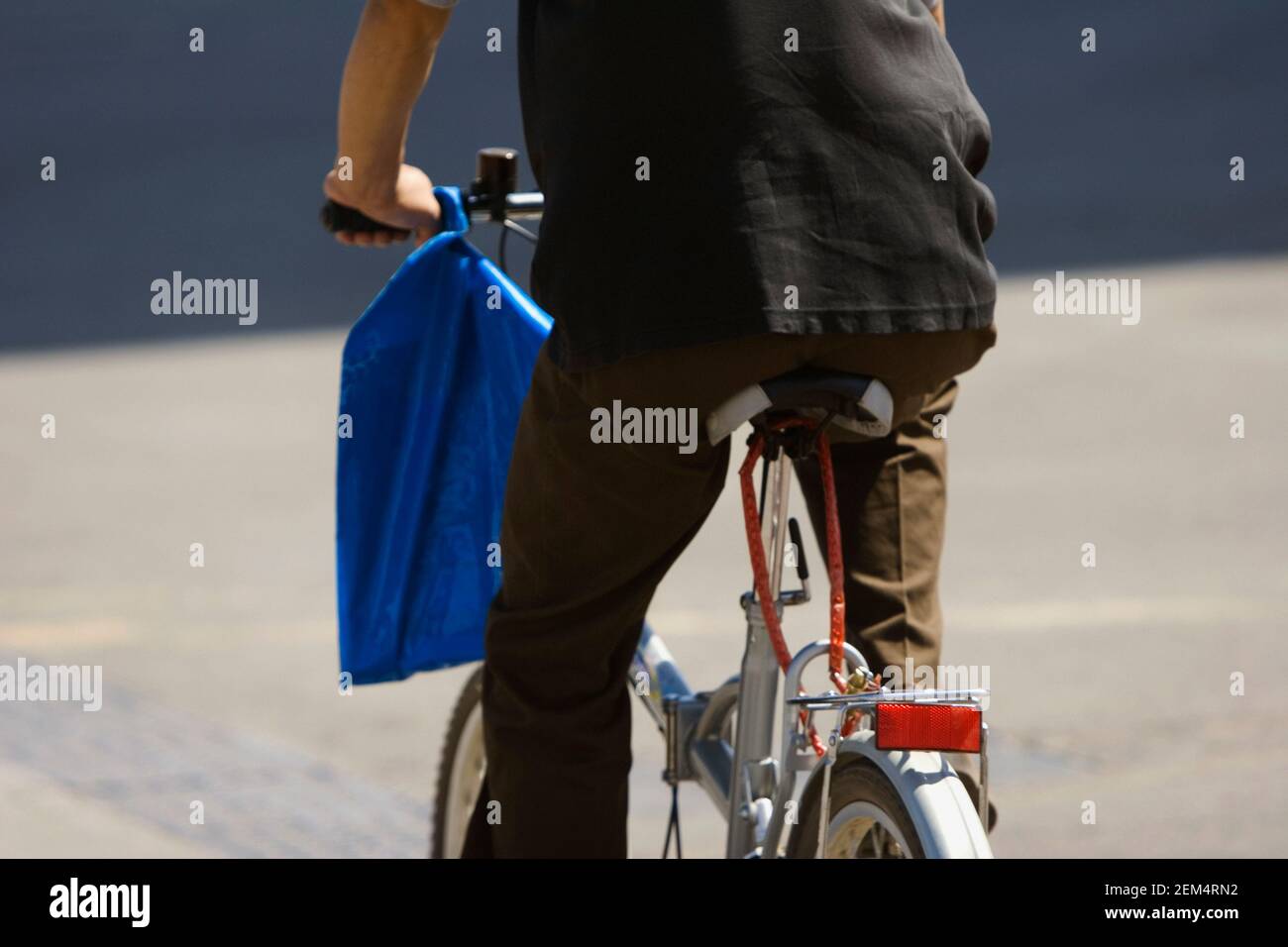 Vista posteriore di un uomo in bicicletta su strada Foto Stock