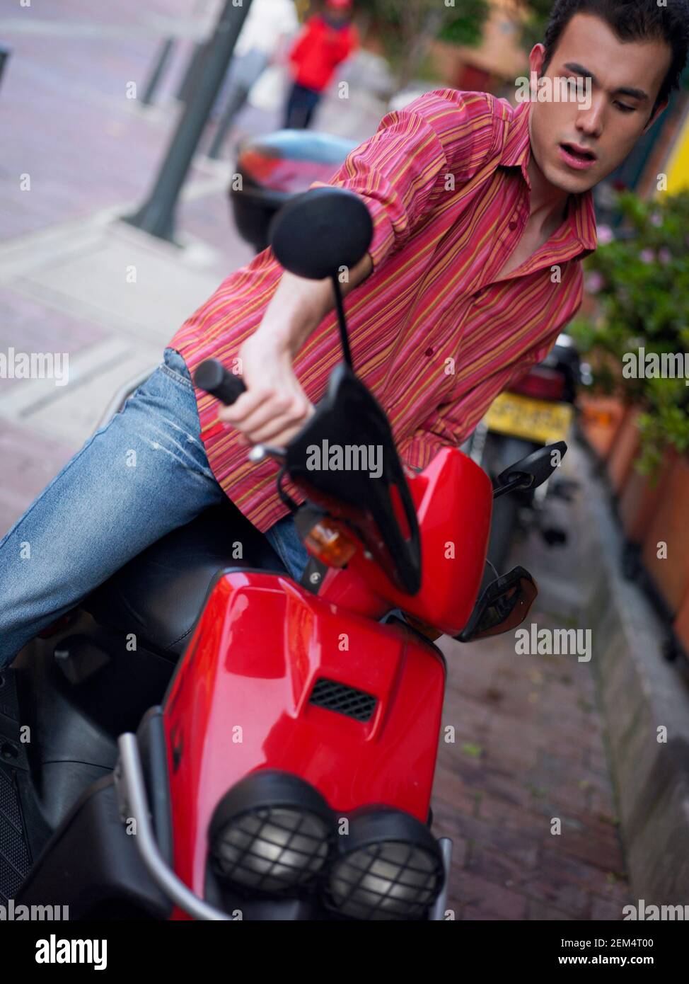 Primo piano di un giovane che guida uno scooter Foto Stock