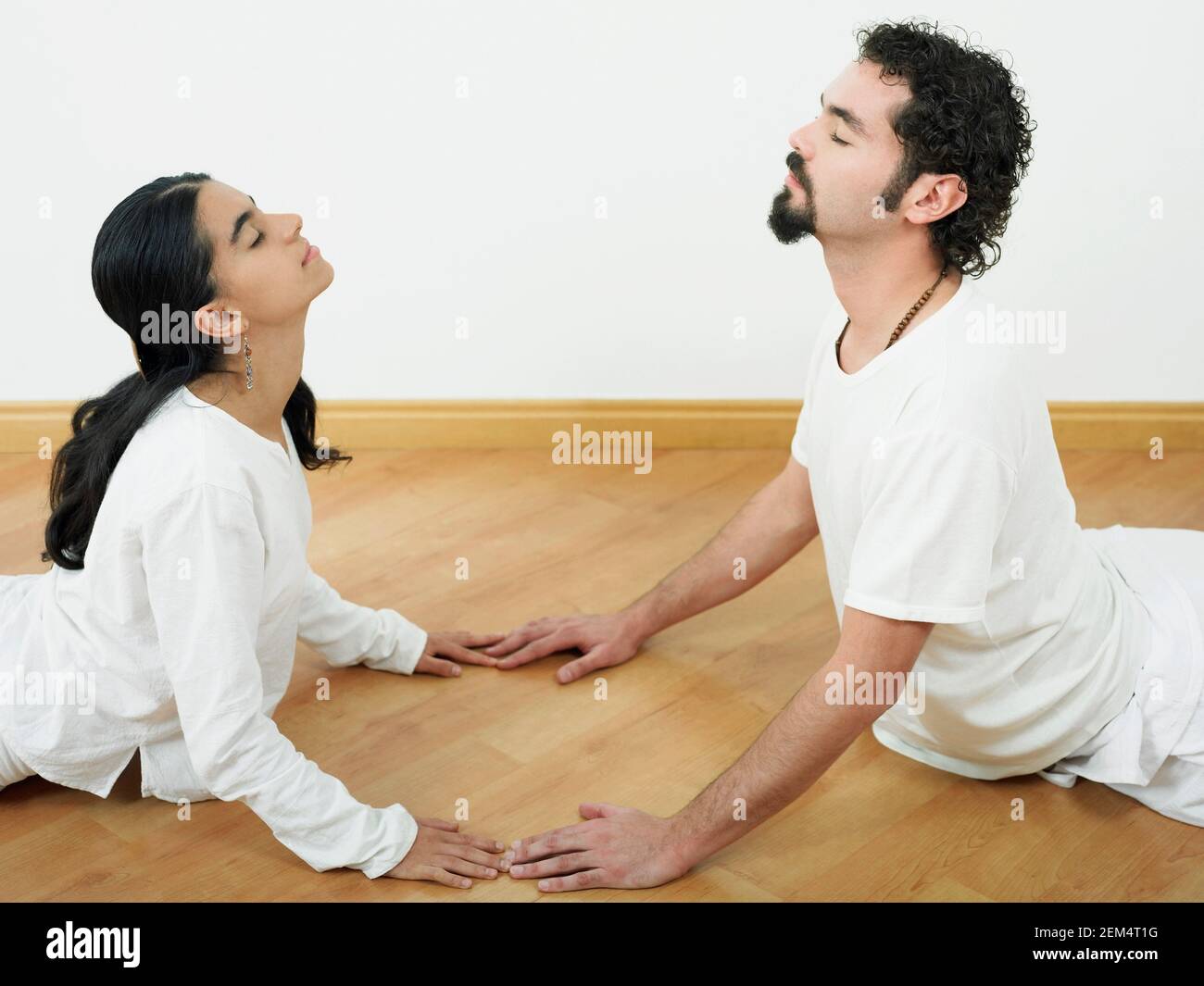 Profilo laterale di un adulto medio con un giovane donna che fa yoga Foto Stock