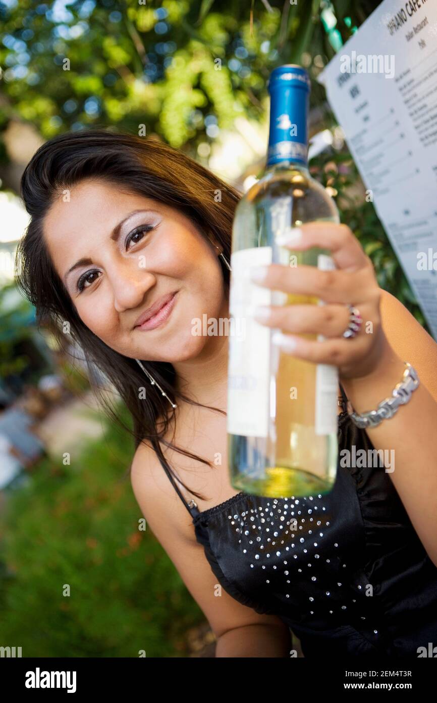 Ritratto di una giovane donna che tiene una bottiglia di bianco vino Foto Stock