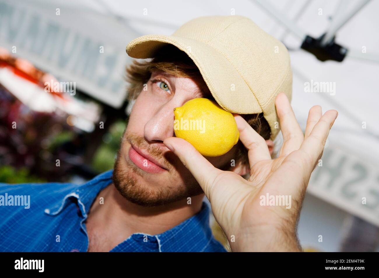 Primo piano di un giovane che tiene un limone sopra di lui occhio Foto Stock