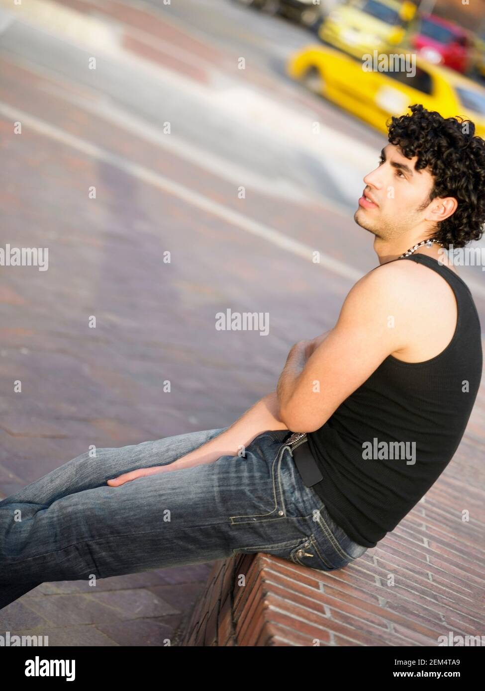 Profilo laterale di un giovane uomo seduto su una sporgenza Foto Stock