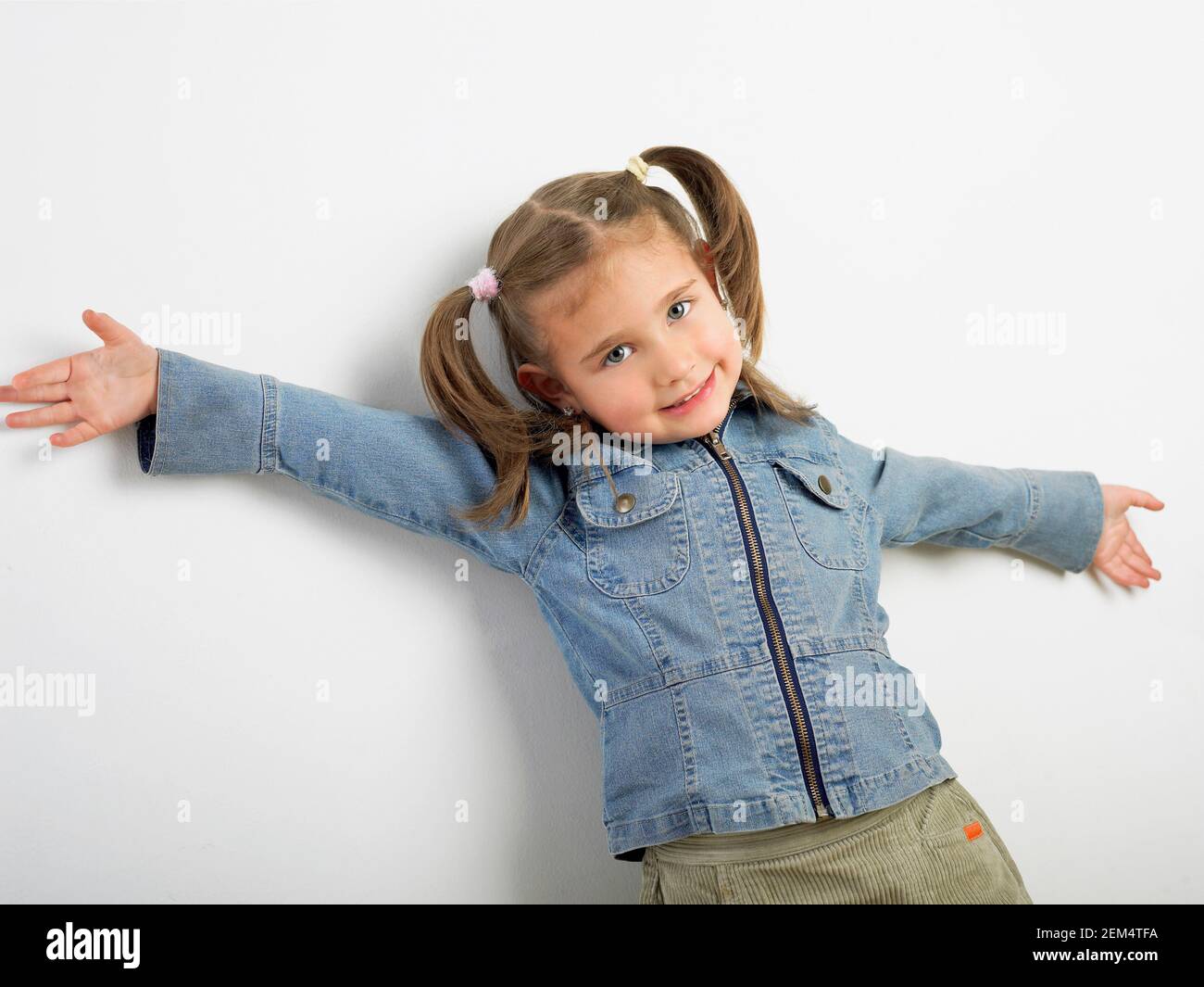 Ritratto di una ragazza in piedi contro un muro e sorridente Foto Stock