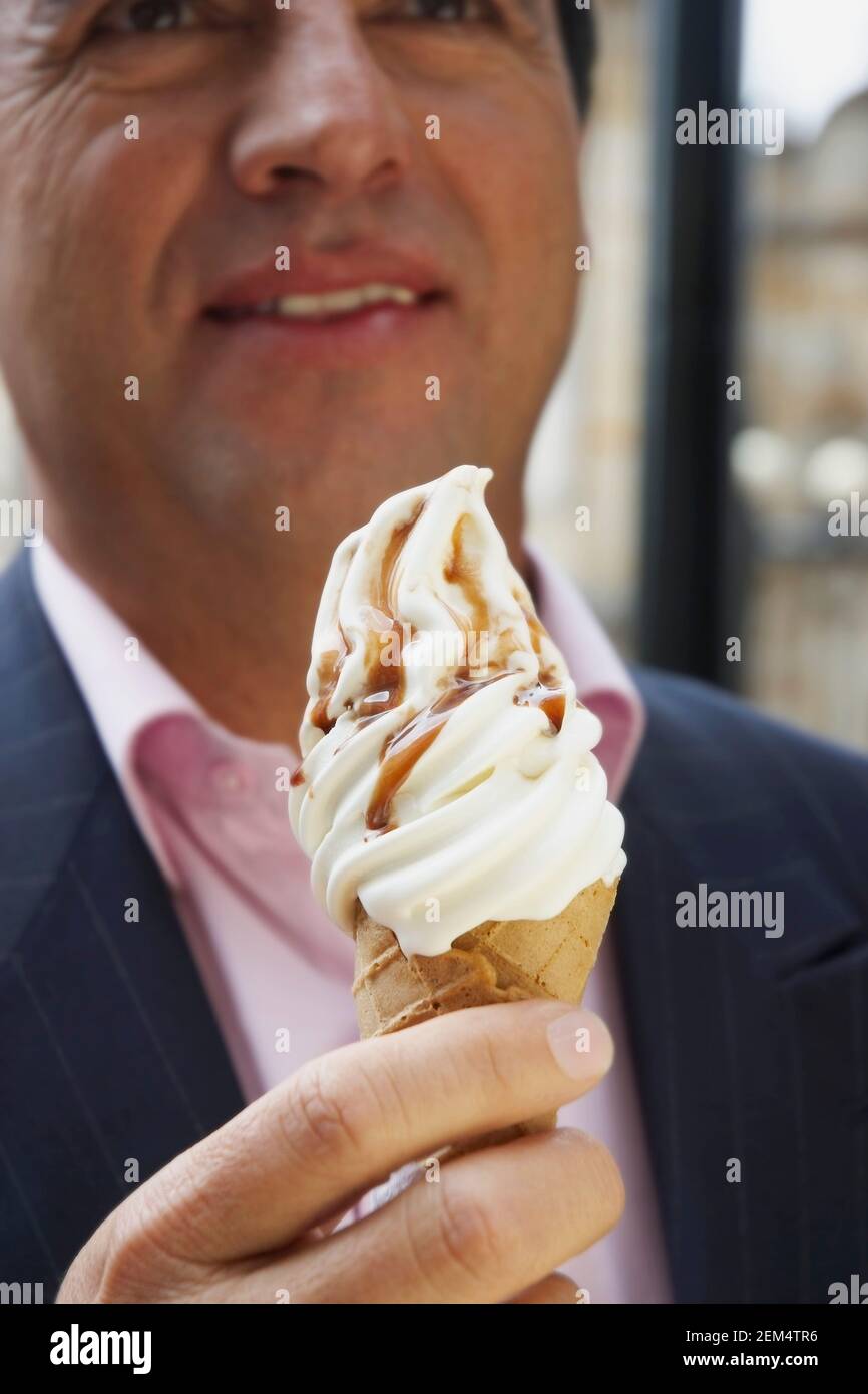 Primo piano di un uomo maturo che tiene un cono gelato Foto Stock