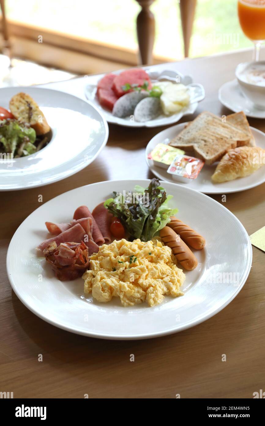 Colazione uova strapazzate con salsiccia di pancetta e insalata su legno sfondo Foto Stock