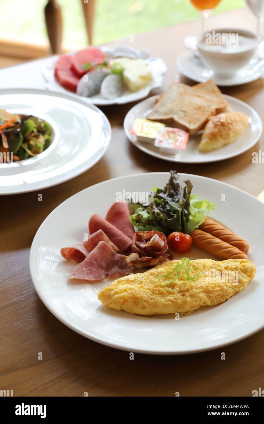 Set colazione frittata con salsicce e pancetta insalata su uno sfondo di legno Foto Stock