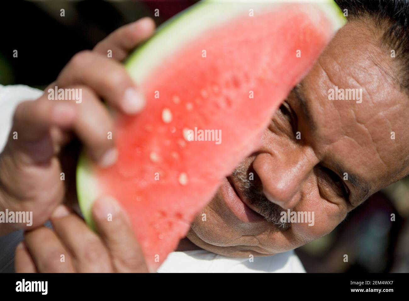 Ritratto di un uomo maturo che tiene una fetta di anguria e sorridendo Foto Stock