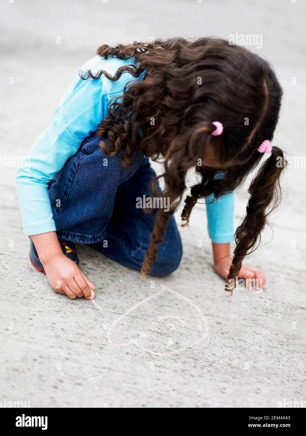 Ragazza disegnando sul pavimento con gesso Foto Stock