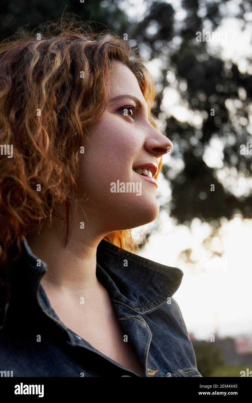 Profilo laterale di una giovane donna che guarda via e sorridente Foto Stock
