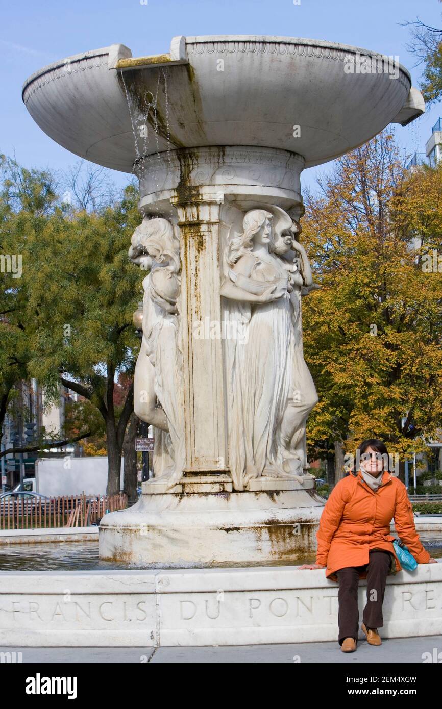 Donna mid adult seduta ad una fontana, DuPont Circle Fountain, DuPont Circle, Washington DC, Washington state, STATI UNITI Foto Stock