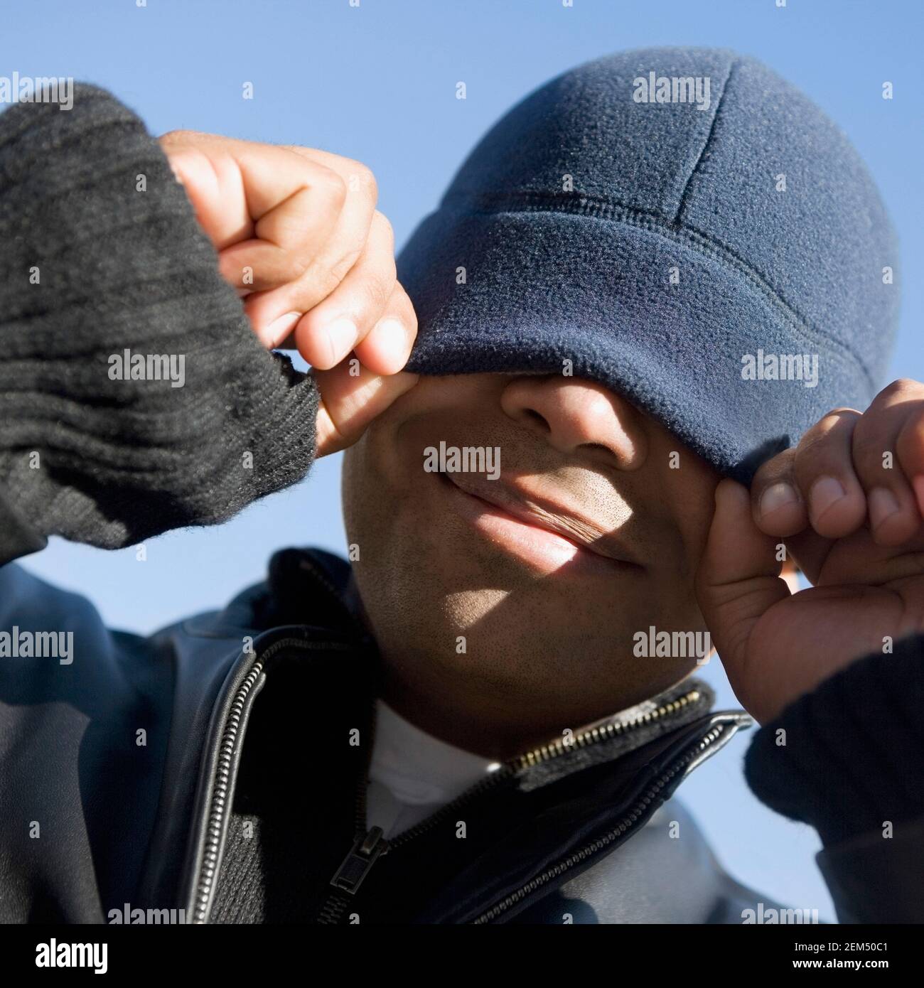 Primo piano di un uomo mid adult che copre gli occhi con il suo cappello Foto Stock