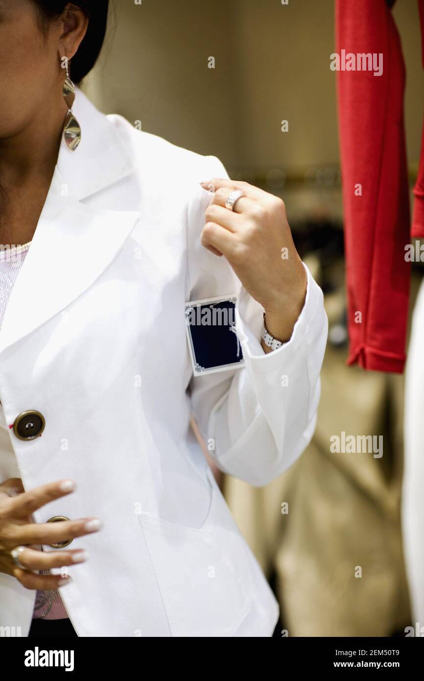 Donna mid adulta che prova su un cappotto in un negozio di abbigliamento, Barcellona, Spagna Foto Stock