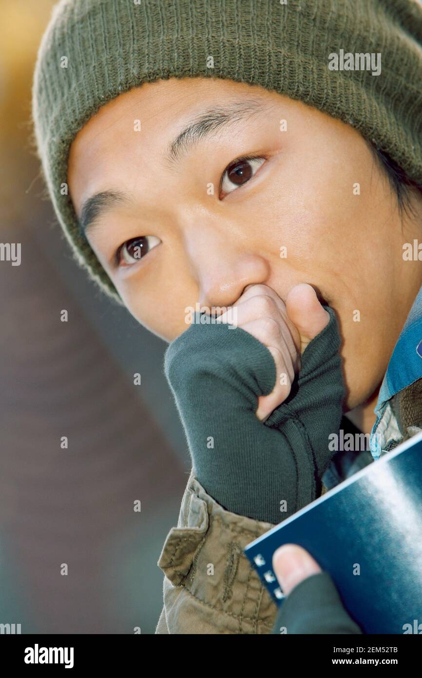 Primo piano di un giovane con la mano sulla sua bocca Foto Stock
