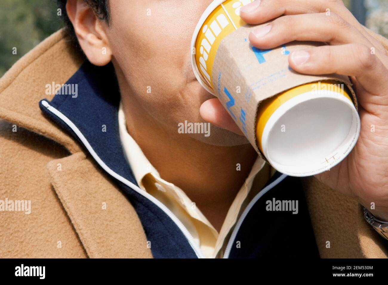 Primo piano di un giovane che beve da una tazza usa e getta Foto Stock