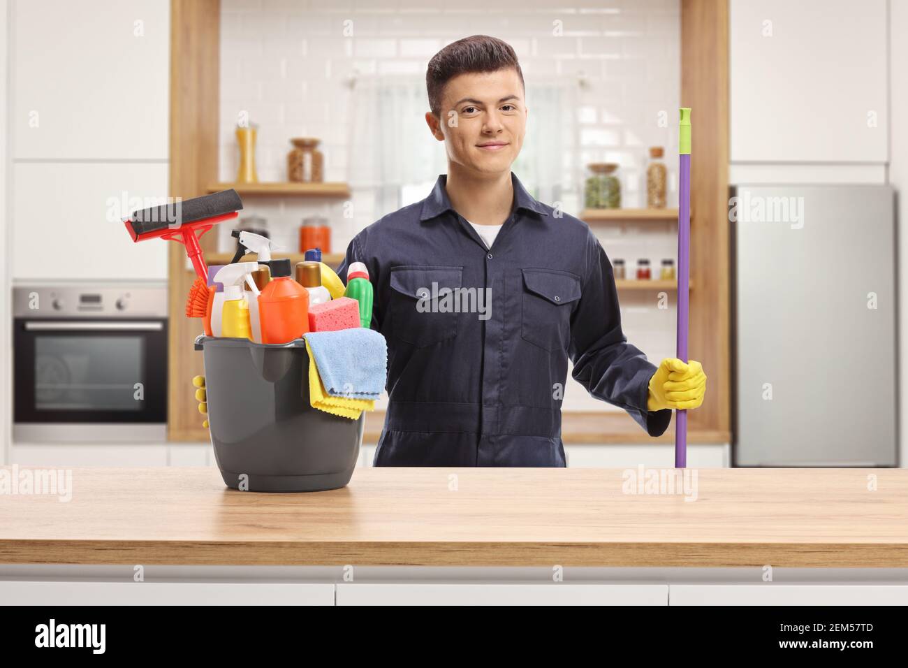 Detergente per giovani in uniforme con secchio e pulizia forniture in cucina Foto Stock