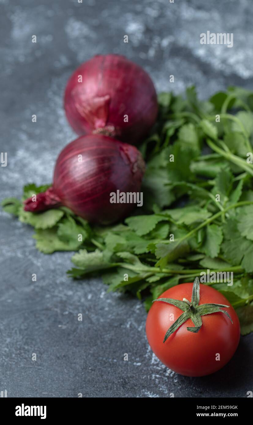 Pomodori rossi freschi con verdi su sfondo marmoreo Foto Stock