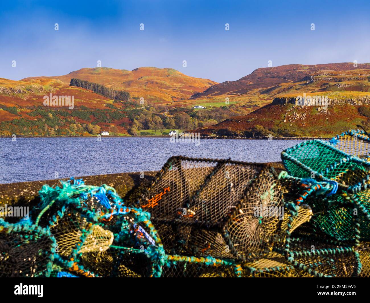 Le pentole da pesca accatastate sul muro del porto sul Isola di Skye in una giornata di sole Foto Stock