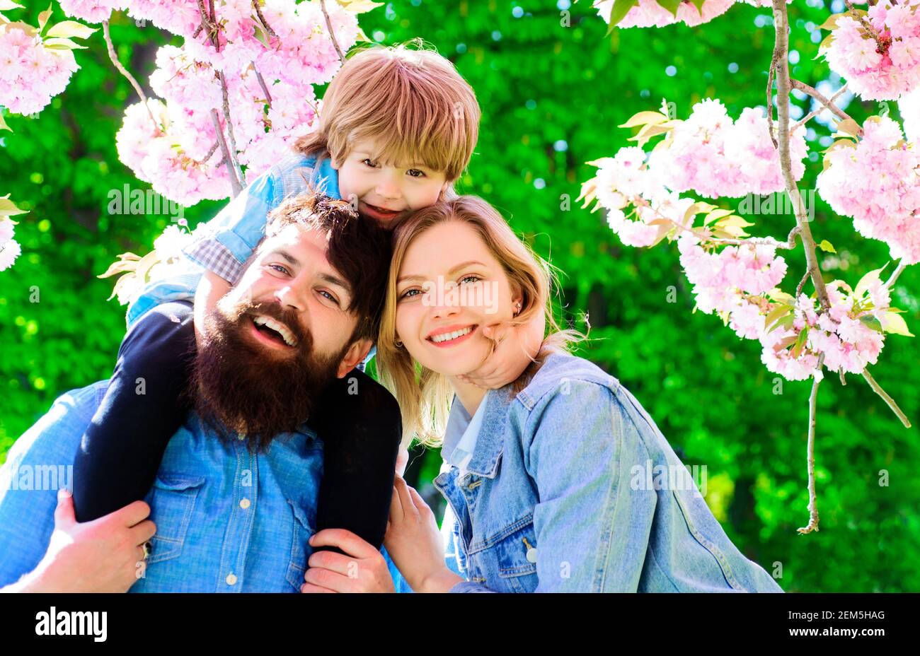 Primavera. Madre, padre e figlio in fiore sakura parco. Passeggiata turistica famiglia in giardino di primavera. Foto Stock