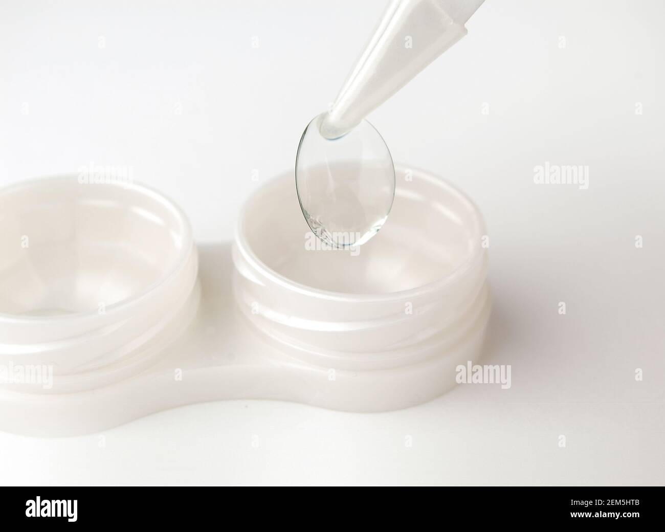 Lenti a contatto in contenitori e pinzette su sfondo grigio. Foto Stock