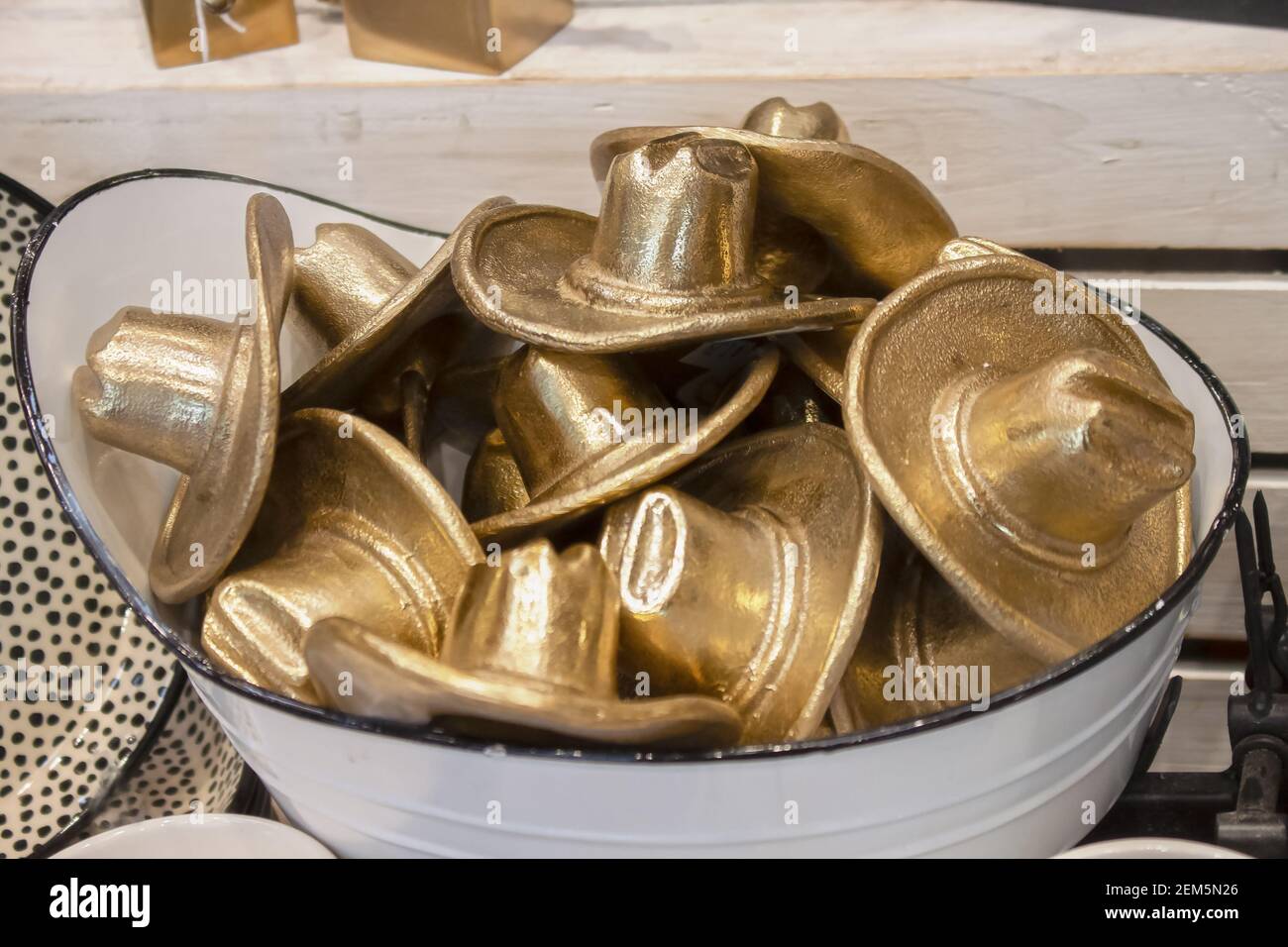 Vasca da bagno piena di cappelli da cowboy in metallo golder seduti su legno ripiano - messa a fuoco superficiale Foto Stock