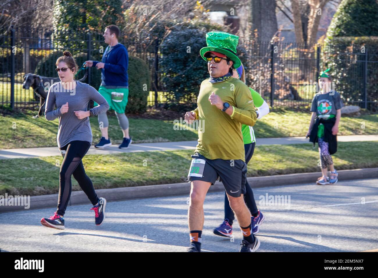 Tulsa USA 3 - 16 - 2019 uomo in sequenza cappello verde circondato da altre persone che camminano in città Strada residenziale nel giorno annuale di San Patrizio r Foto Stock