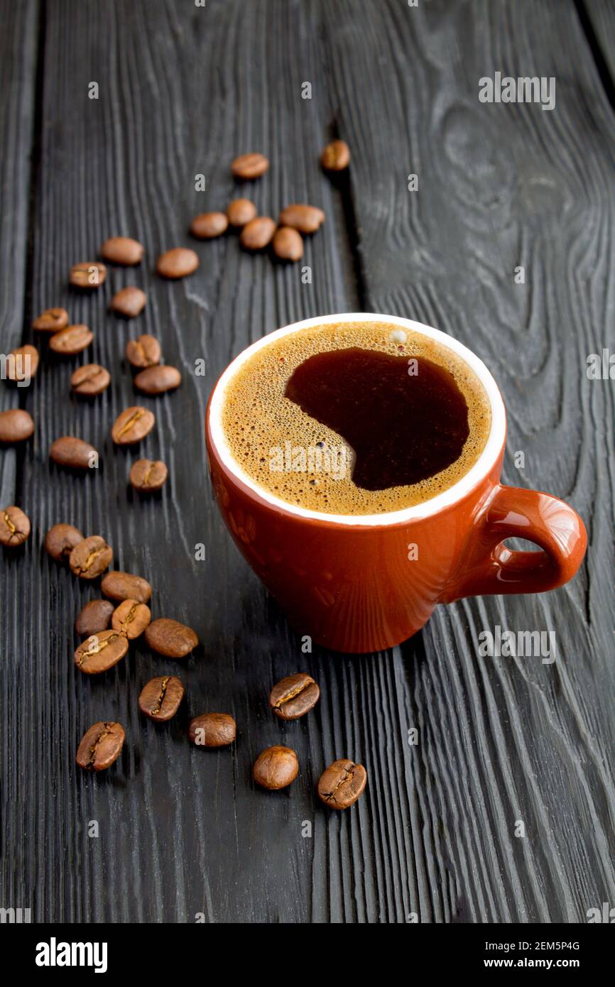 Caffè nero nella tazza di ceramica marrone su fondo di legno nero. Spazio di copia. Posizione verticale. Foto Stock