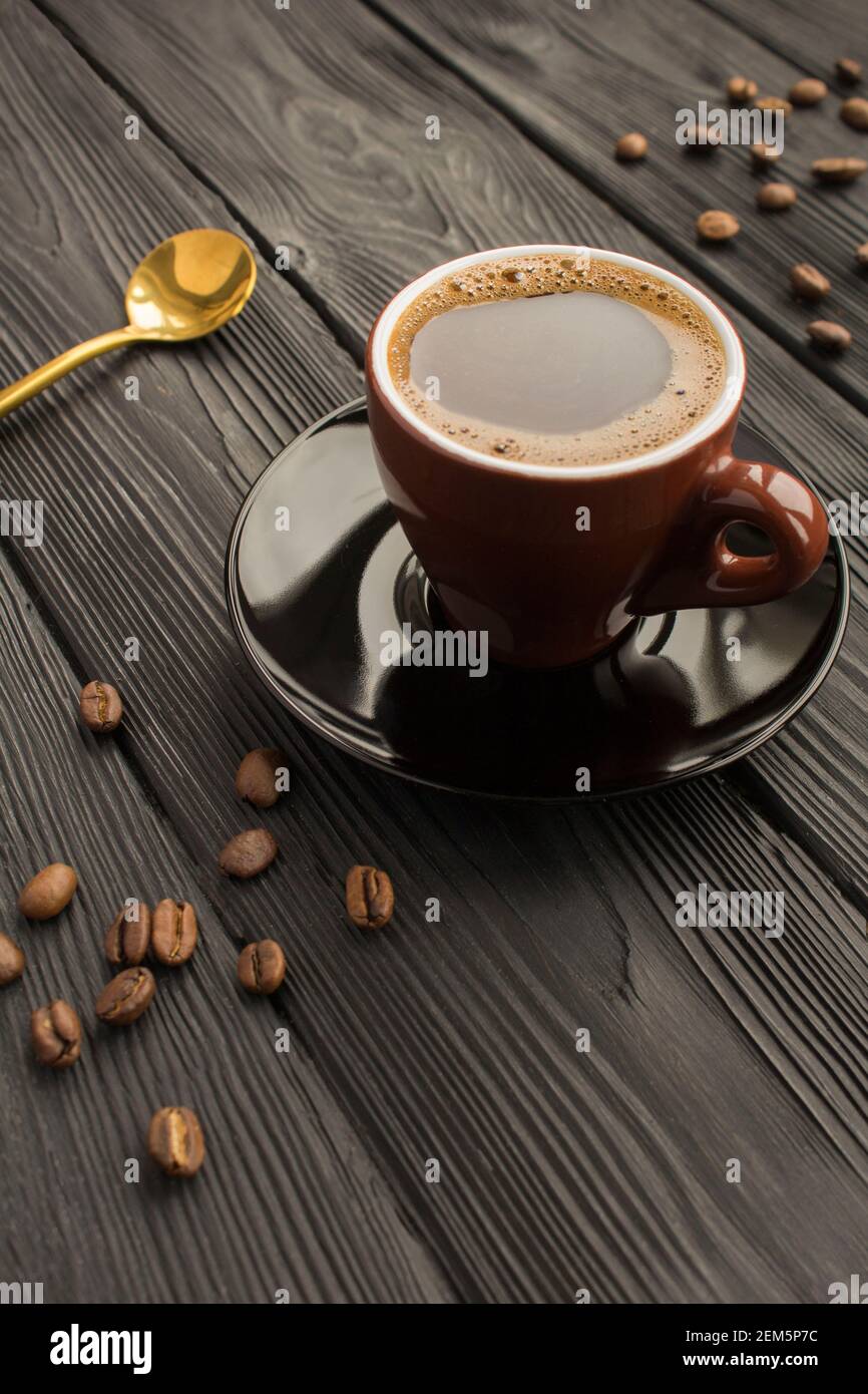 Caffè nero nella tazza di ceramica marrone su fondo di legno nero. Spazio di copia. Posizione verticale. Foto Stock