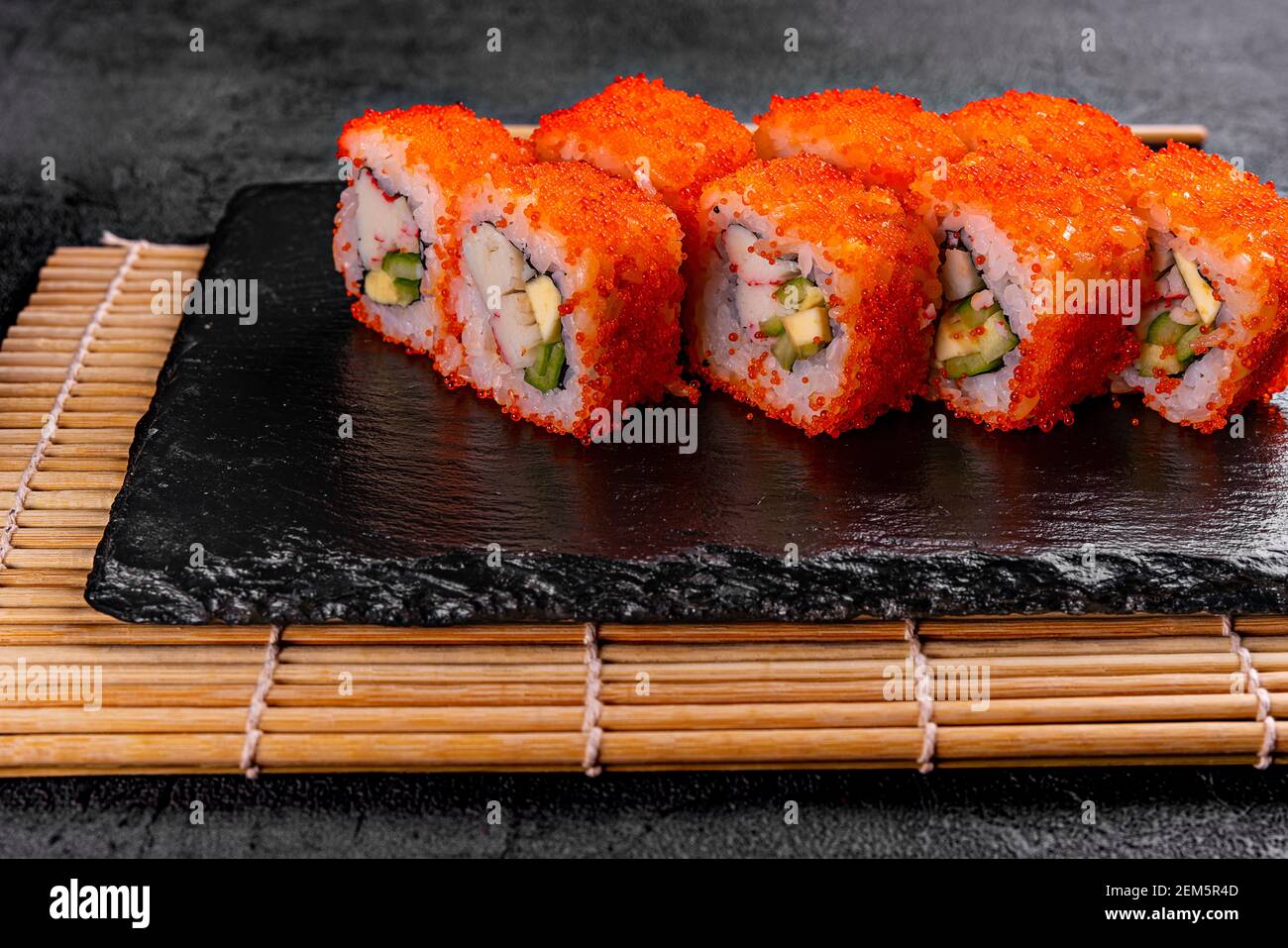 Rotolo di sushi Golden dragon con granchio, salmone, cetriolo, semi di sesamo e formaggio cremoso su sfondo nero. Vista dall'alto Foto Stock