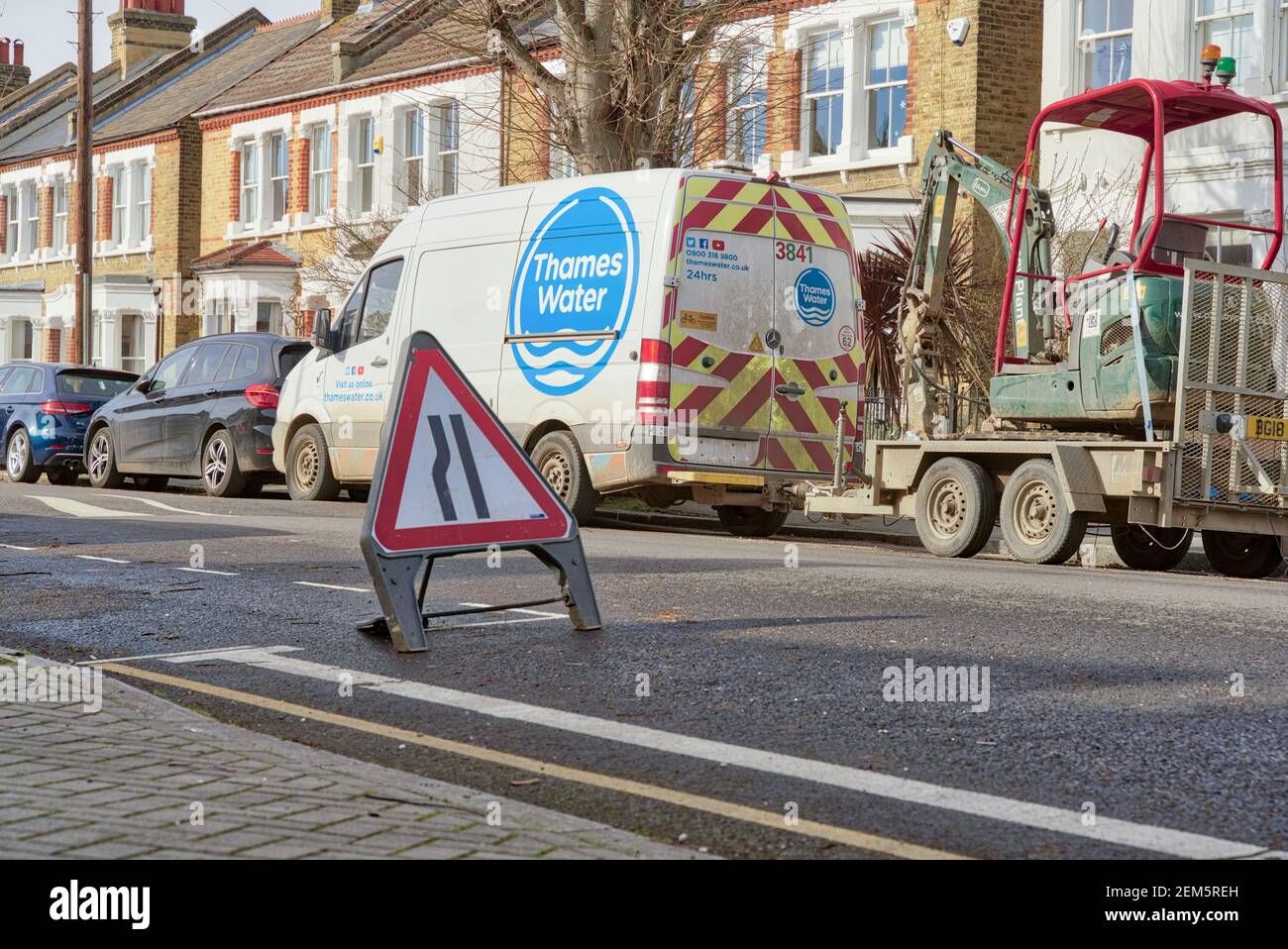 Tamigi Water van trainare un digger parcheggiato a lato della strada lungo una fila di case terrazza, strada sempre segno stretto posto su strada, Londra Foto Stock
