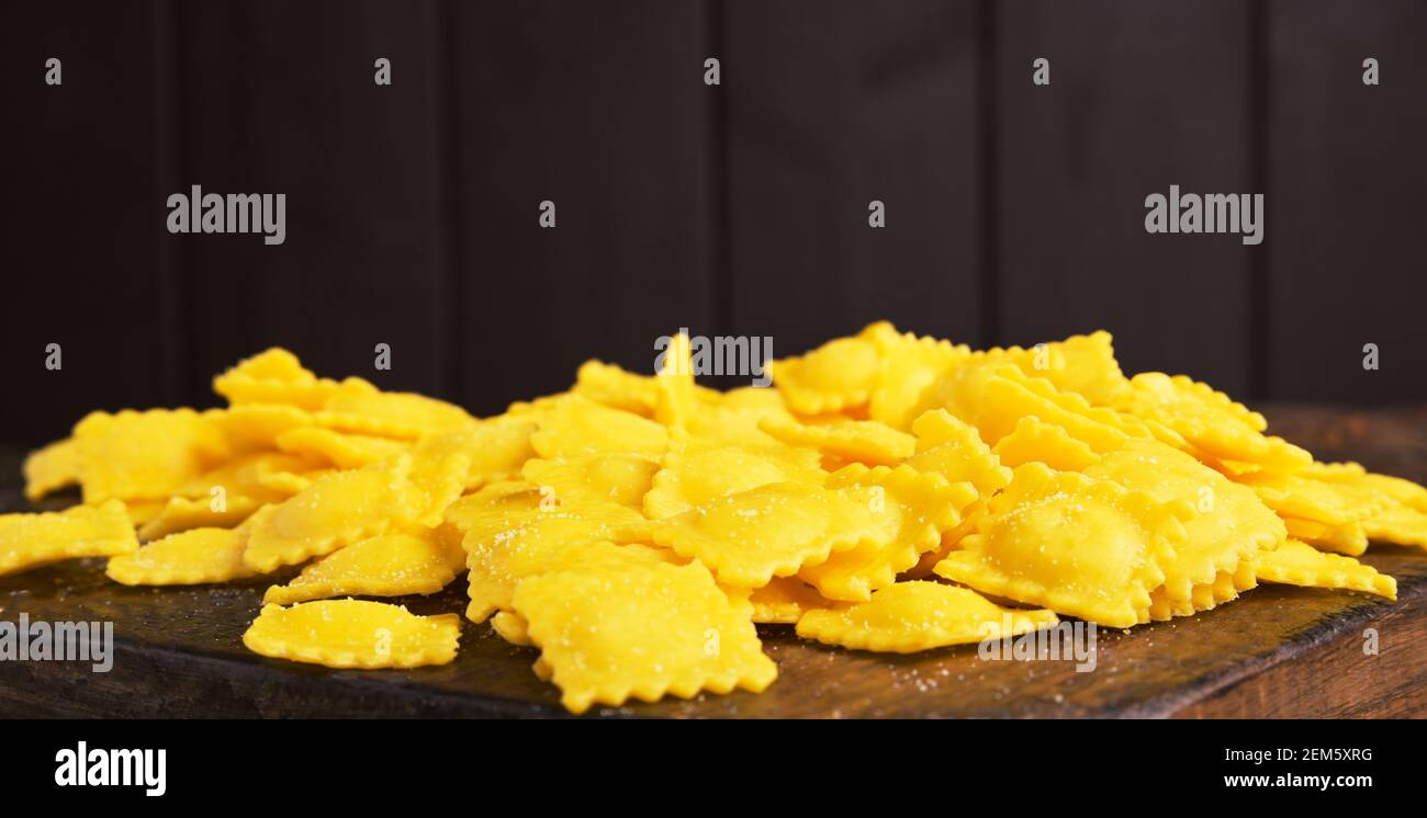 Ravioli piccoli con formaggio o carne da cuocere in brodo, piatto tradizionale per celebrazioni in italia, regione Emilia Romagna. Pasta fresca fatta in casa con ripieno su un tavolo di legno. Spazio di copia Foto Stock
