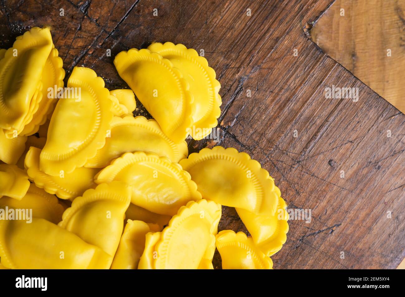 Ravioli piccoli con contorni ondulati, formaggio o carne da cuocere in brodo, piatto tradizionale per celebrazioni in italia, regione Emilia Romagna. Pasta fresca fatta in casa con ripieno su un tavolo di legno. Spazio di copia Foto Stock