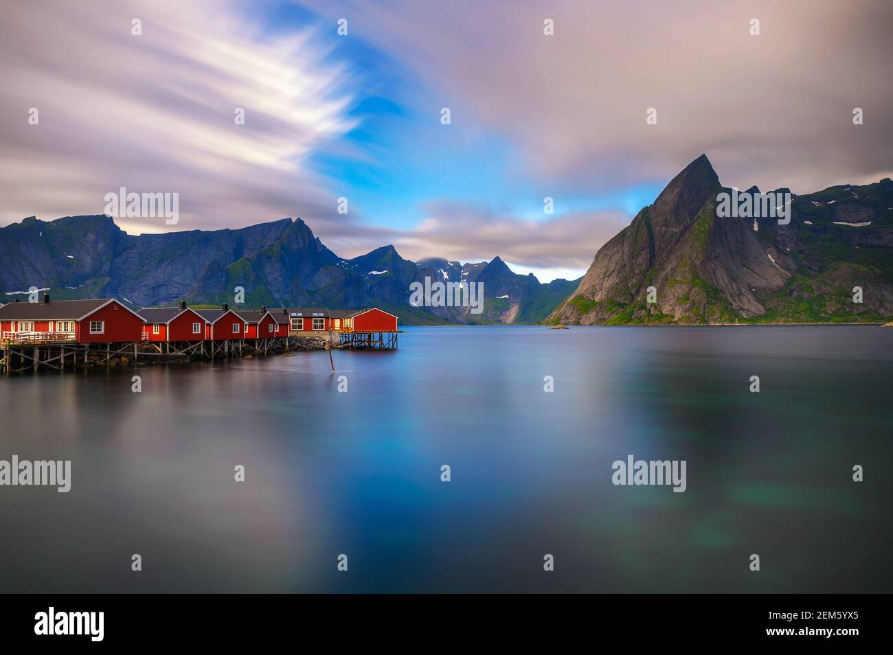 Tramonto sul monte Olstind e cabine di pesca rosse nelle Isole Lofoten, Norvegia Foto Stock