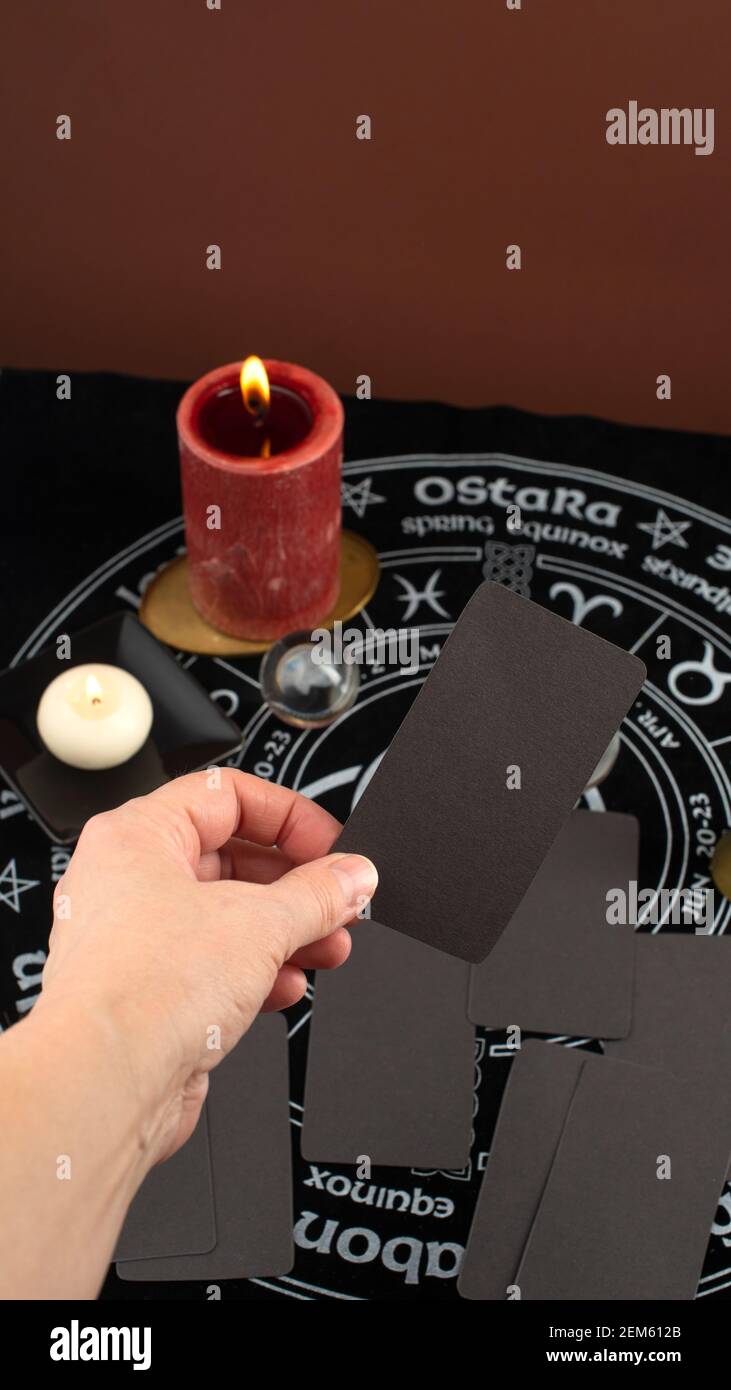 Mano che tiene la carta vuota davanti a sfondo mistico con oggetti occulti e magici. Rituale di narrazione e divinazione della Fortune. Foto Stock