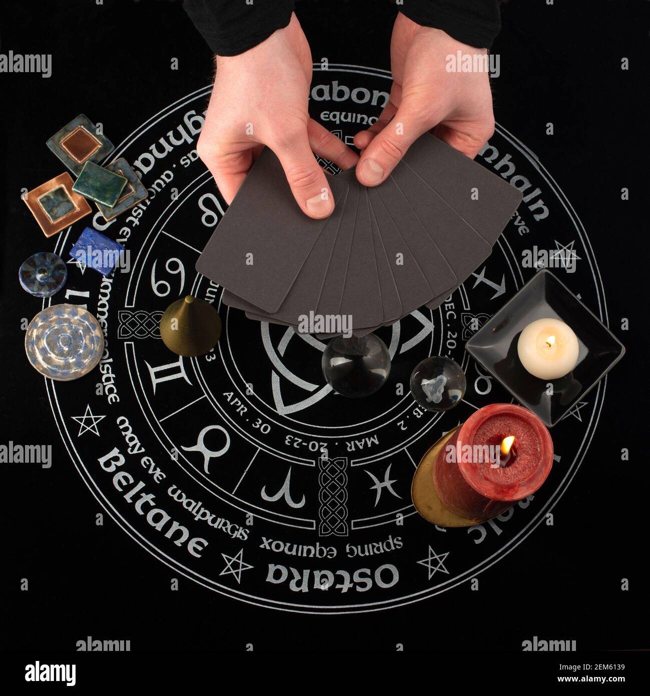 Mano che tiene la carta vuota davanti a sfondo mistico con oggetti occulti e magici. Rituale di narrazione e divinazione della Fortune. Foto Stock