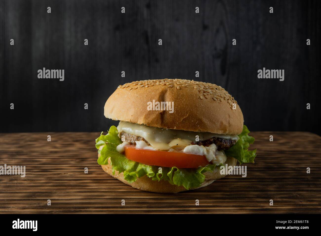 burger con lattuga, pomodoro e maionese servito su un rustico tavolo di legno, con copyspace Foto Stock