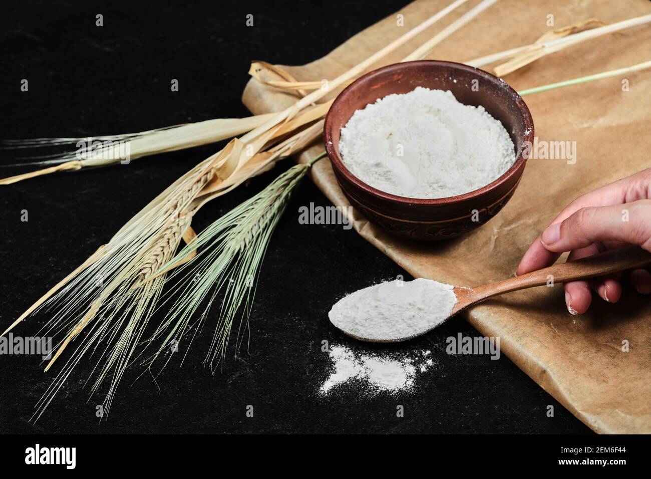 Tenere a mano un cucchiaio di farina e farina nel recipiente con grano Foto Stock