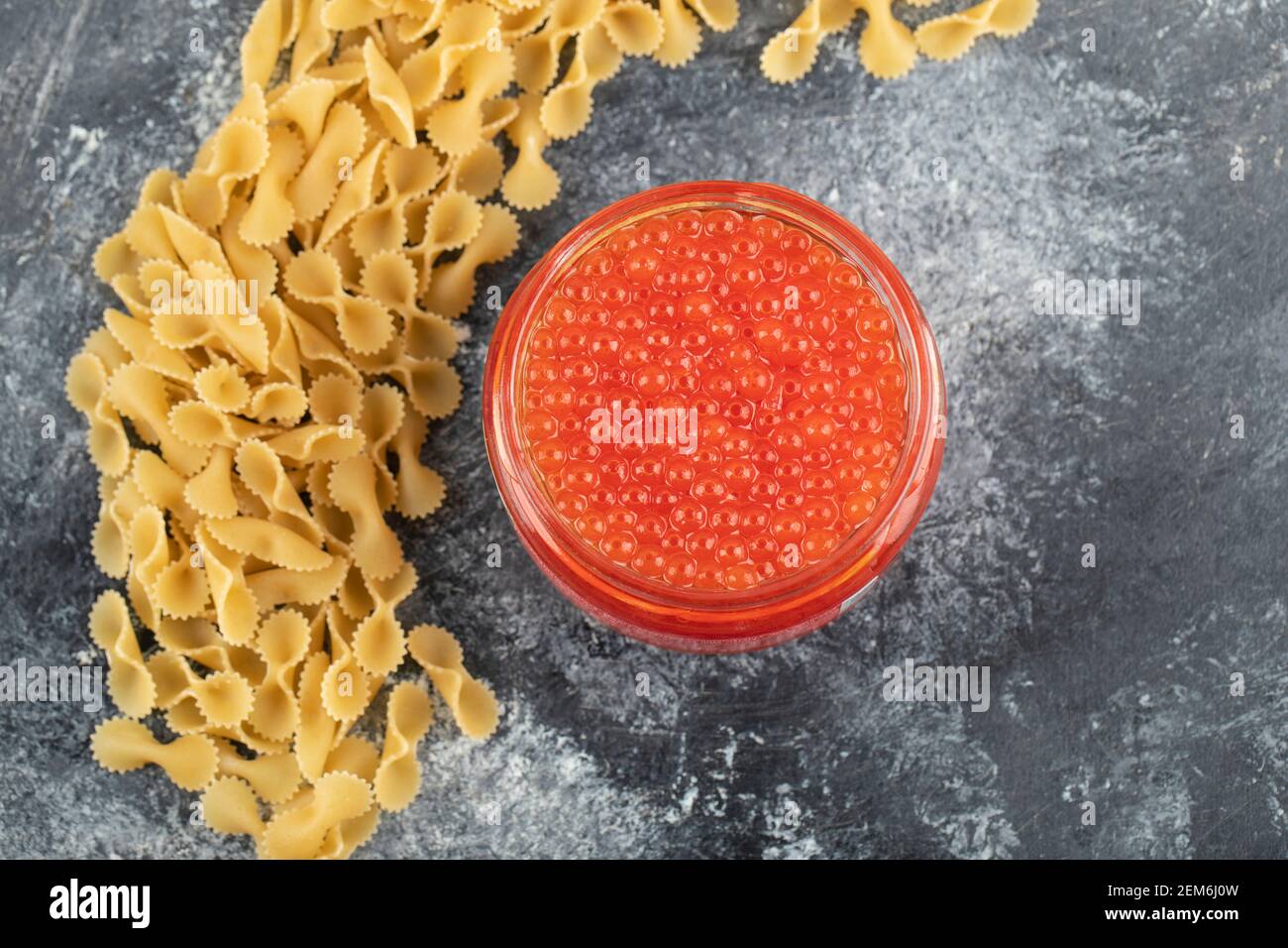 Un piatto di vetro di caviale di storione rosso con pasta cruda Foto Stock