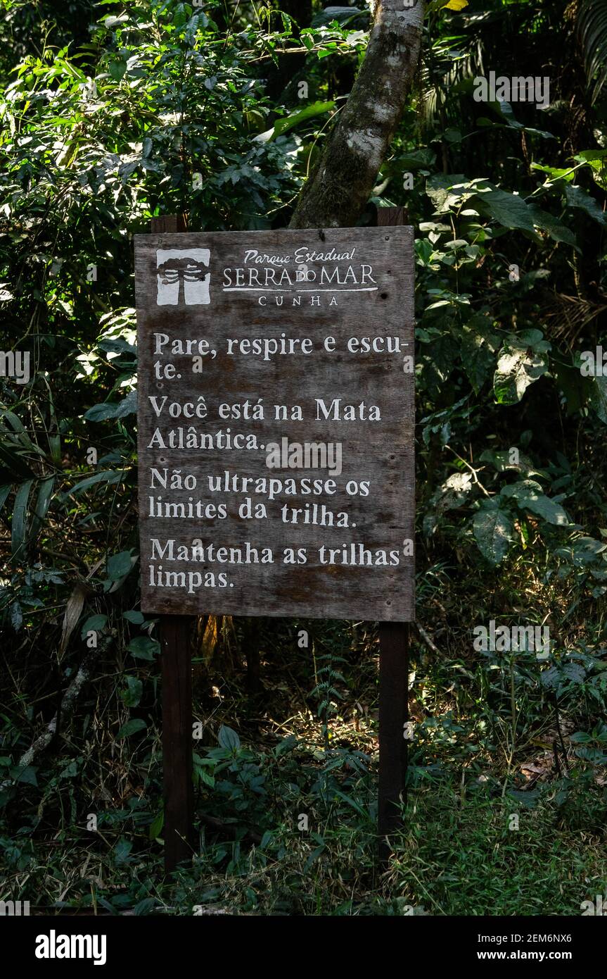 Un cartello in legno con le istruzioni di sicurezza e le raccomandazioni per i visitatori del parco della tenuta Serra do Mar mentre si trovano nei sentieri escursionistici del nucleo di Cunha. Foto Stock