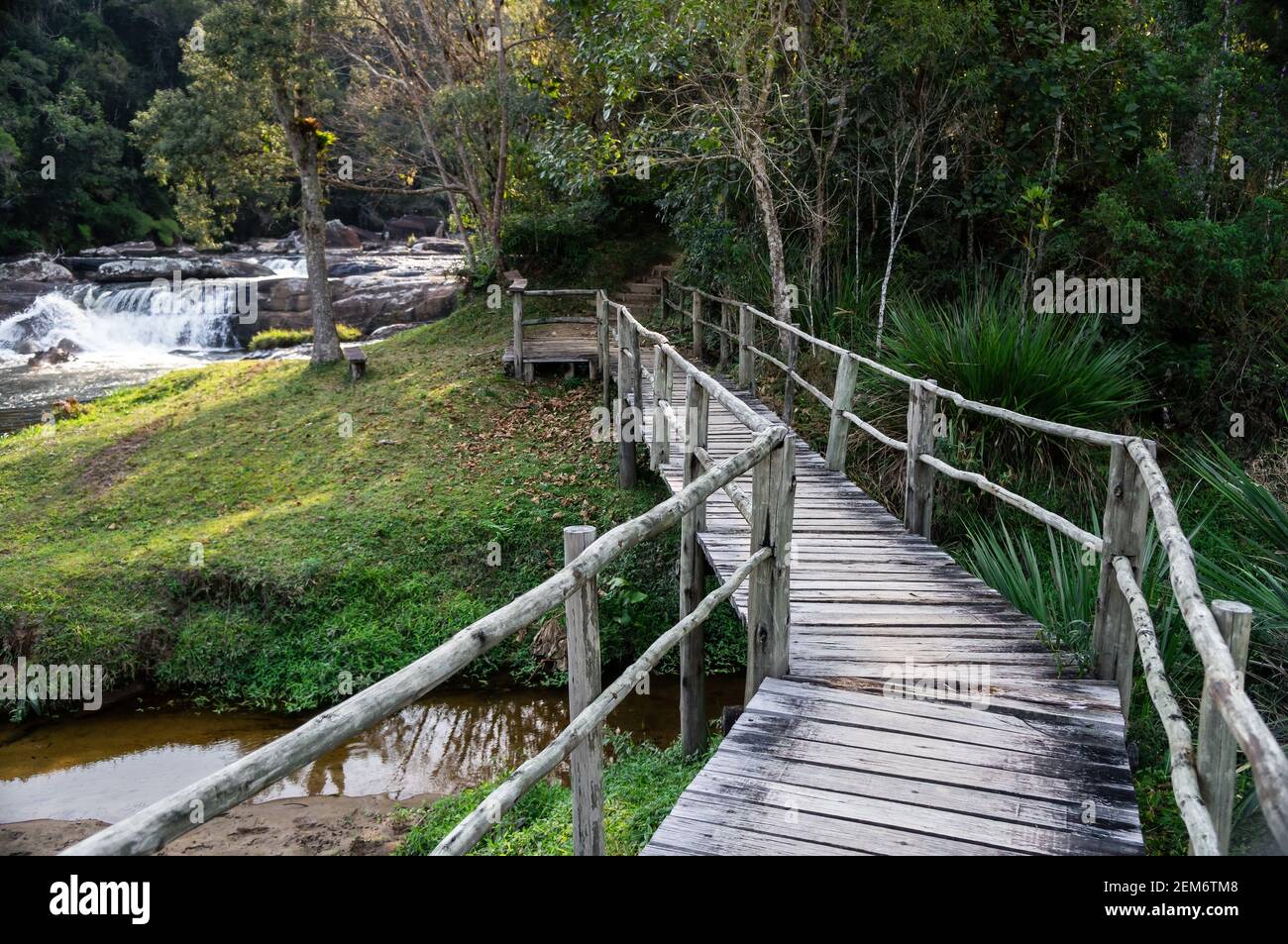 Il ponte di legno all'inizio del sentiero escursionistico del fiume Paraibuna con una cascata in fondo. Si tratta di un percorso autoguidato di 1700 m a Cunha. Foto Stock