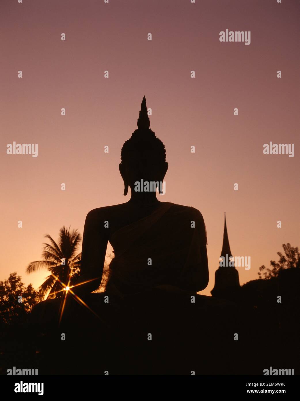 Asia, Thailandia, Sukothai, Wat Mahathat tempio buddista silhouette della statua gigante in pietra Buddha seduto Foto Stock