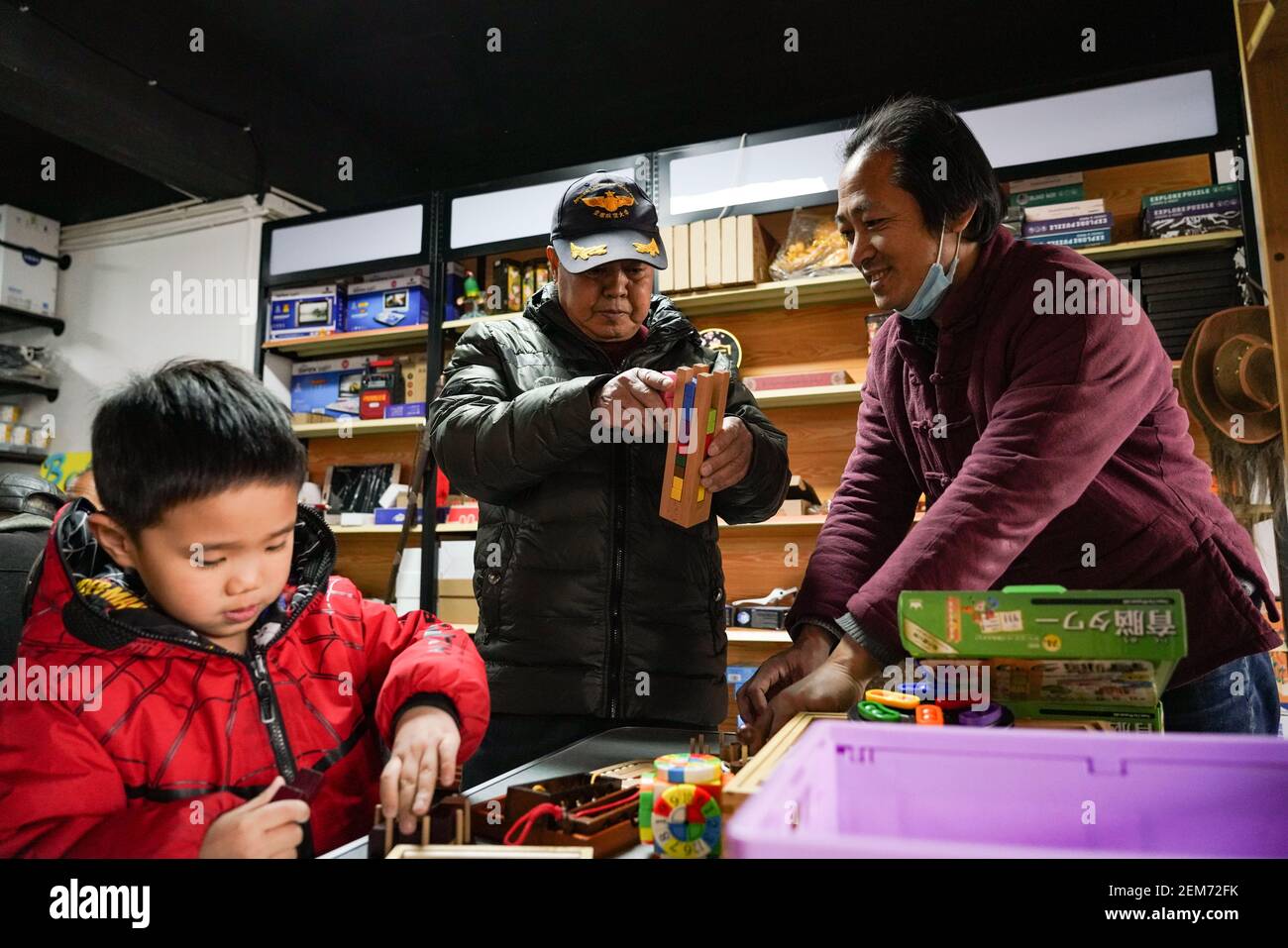 Pechino, Cina. 23 Feb 2021. Un cliente (C) e il suo nipote (L) giocano a un negozio di giocattoli per anziani a Pechino, capitale della Cina, 23 febbraio 2021. Il negozio di giocattoli di proprietà di Song Delong, che ha circa 400 tipi di giocattoli, specialmente per gli anziani, serve non solo come un negozio di giocattoli, ma un luogo popolare per il tempo libero e sociale per gli anziani locali. Credit: Chen Zhonghao/Xinhua/Alamy Live News Foto Stock