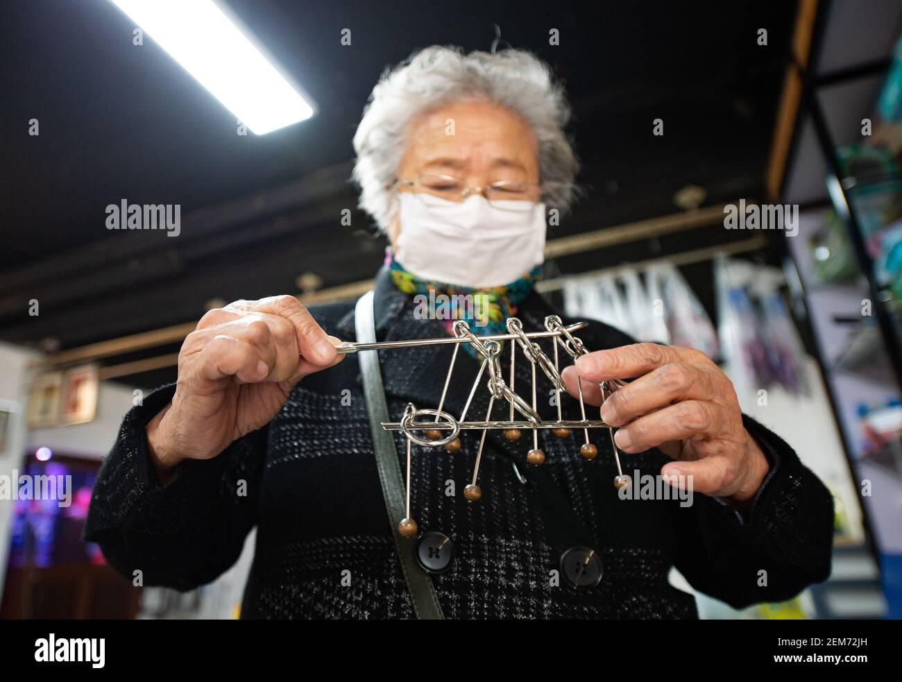 Pechino, Cina. 23 Feb 2021. Un cliente gioca un gioco di puzzle in un negozio di giocattoli per gli anziani a Pechino, capitale della Cina, 23 febbraio 2021. Il negozio di giocattoli di proprietà di Song Delong, che ha circa 400 tipi di giocattoli, specialmente per gli anziani, serve non solo come un negozio di giocattoli, ma un luogo popolare per il tempo libero e sociale per gli anziani locali. Credit: Chen Zhonghao/Xinhua/Alamy Live News Foto Stock