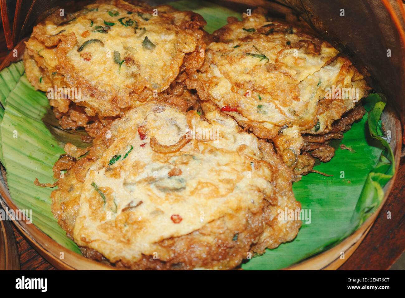 Frittelle soffici per la colazione con cipolline verdi e pane tostato fresco pane su una superficie di foglia di banana Foto Stock