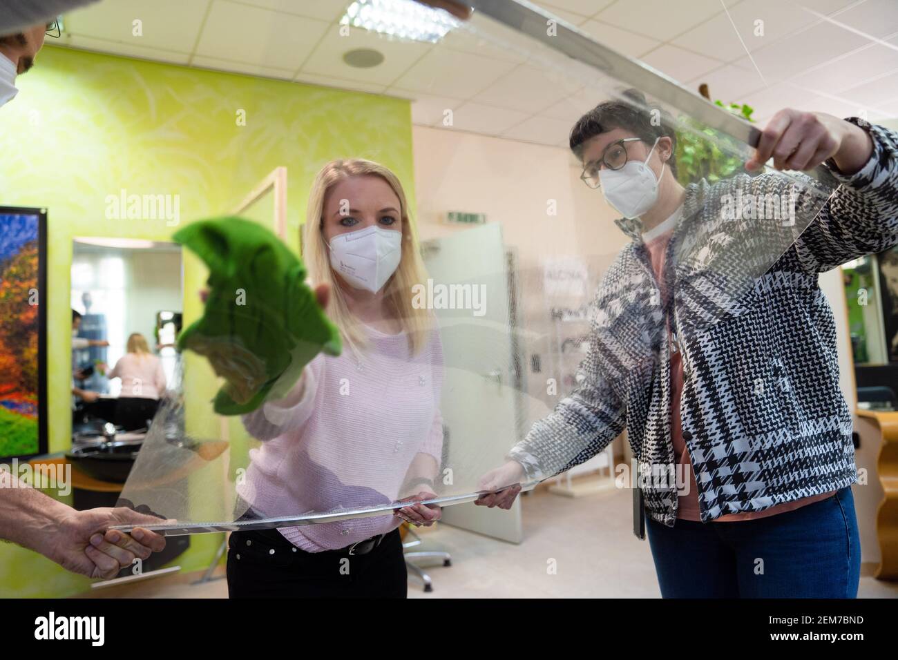 Schweinfurt, Germania. 24 Feb 2021. Il parrucchiere Linda (M) pulisce i divisori nel salone di parrucchiere 'Extra Locke' insieme al parrucchiere Nina (r). Gli appuntamenti sono completamente prenotati e i preparativi sono in pieno svolgimento: Da Lunedi (01.03.2021) i parrucchieri sono autorizzati ad aprire di nuovo. Credit: Nicolas Armer/dpa/Alamy Live News Foto Stock