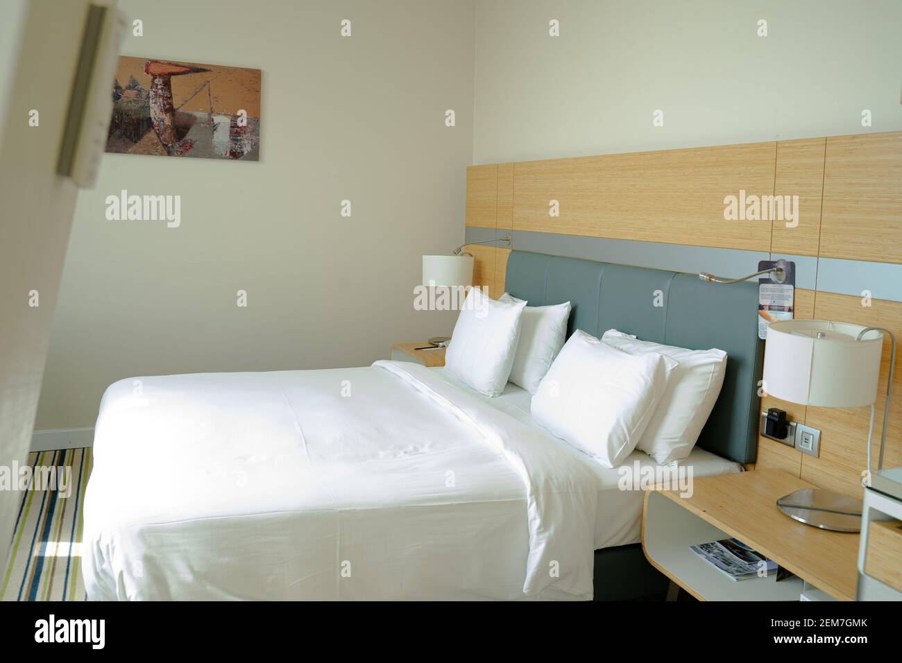 Letto king size in una camera vuota e moderna e accogliente mansarda dell'hotel, luminosa attraverso la finestra Foto Stock