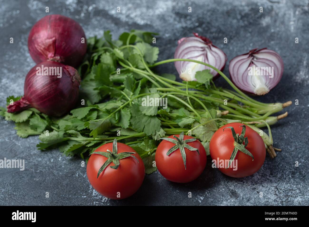 Pomodori rossi freschi con verdi su sfondo marmoreo Foto Stock