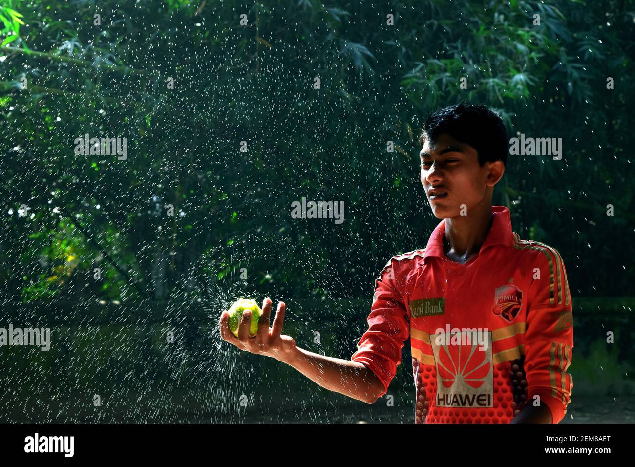 Cumilla, Bangladesh - 24 novembre 2017: Il ragazzo sta spruzzando acqua con una palla di cricket Foto Stock